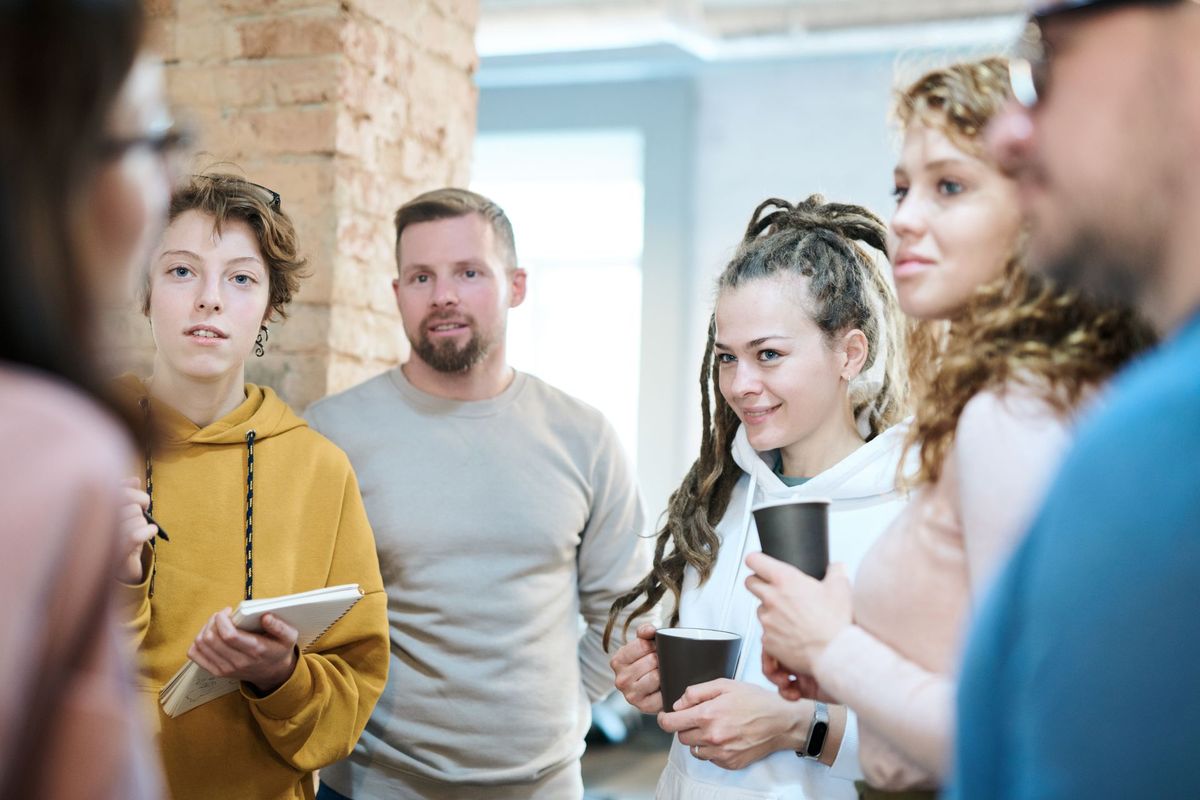 Un grupo de personas conversa de pie, con un café en la mano